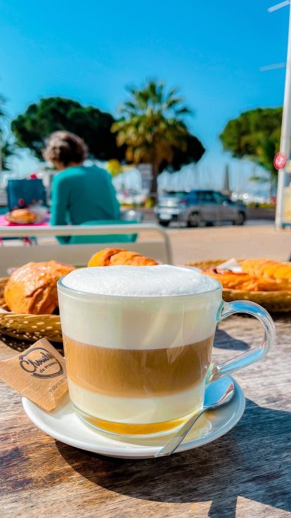 Café et viennoiseries en terrasse, le port en fond